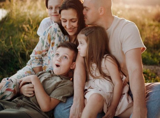 A joyful family enjoying quality time together on a sunset-lit meadow.