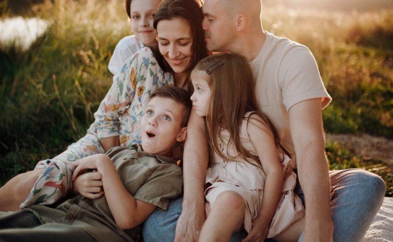 A joyful family enjoying quality time together on a sunset-lit meadow.